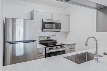 A modern kitchen with a stainless steel refrigerator, oven, and microwave.